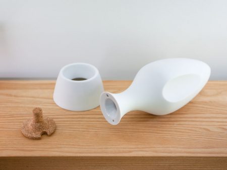 Atmosphärische Aufnahme der Amphore MILOS liegend auf einem Holzbrett. Daneben Korken und Standfuß